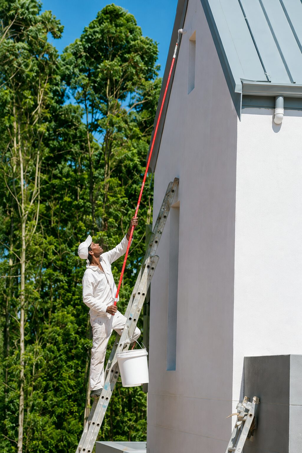 Exterior painting reference — painter on ladder cutting a clean line